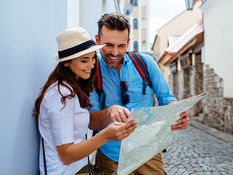 Um casal em Lua de Mel planejando viagens e olhando um mapa.